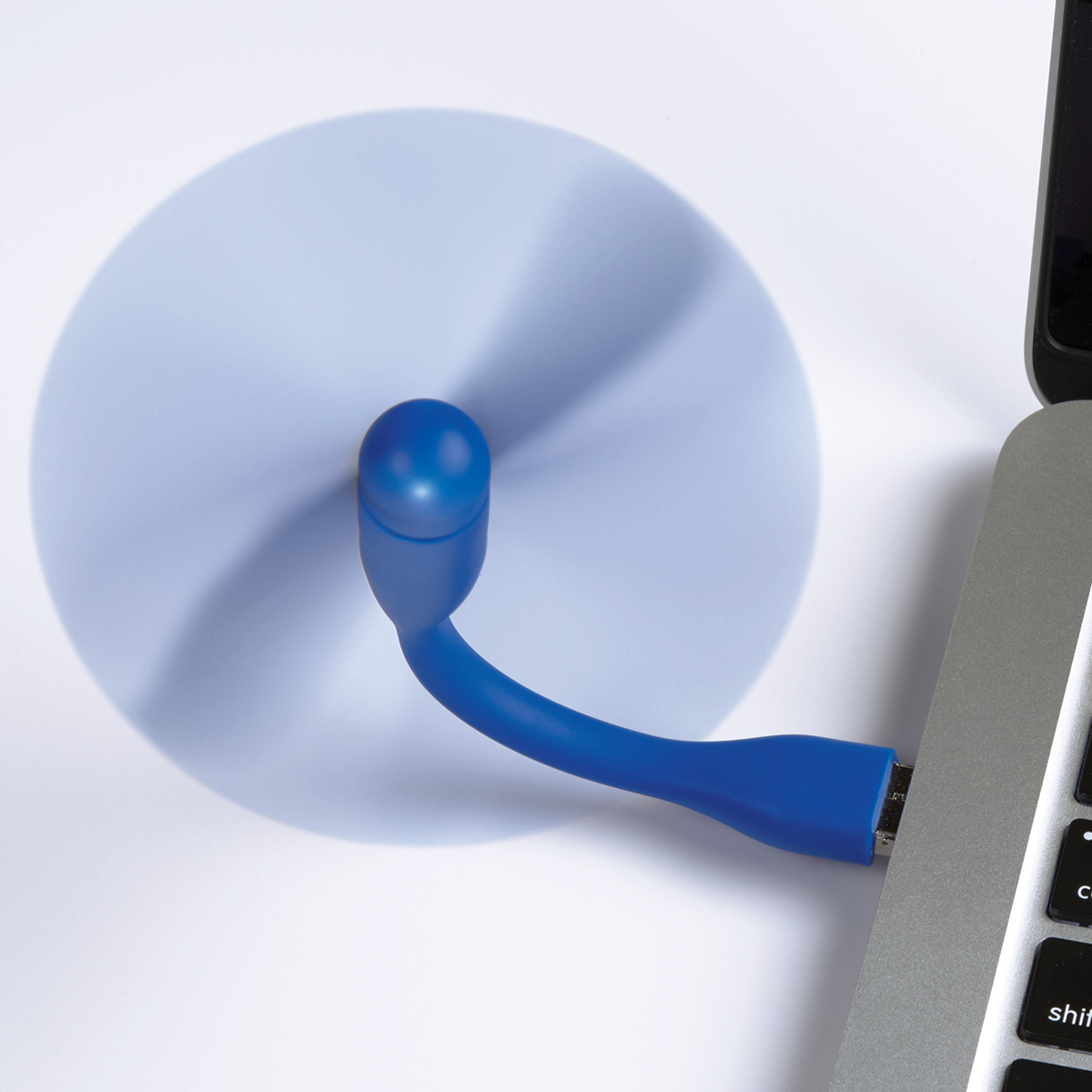 Mini USB Fan with 3-Way Connector in Blue  flexible material attached to a laptop on a desk, providing personal cooling while connected through the device charging port in an everyday workspace setting.