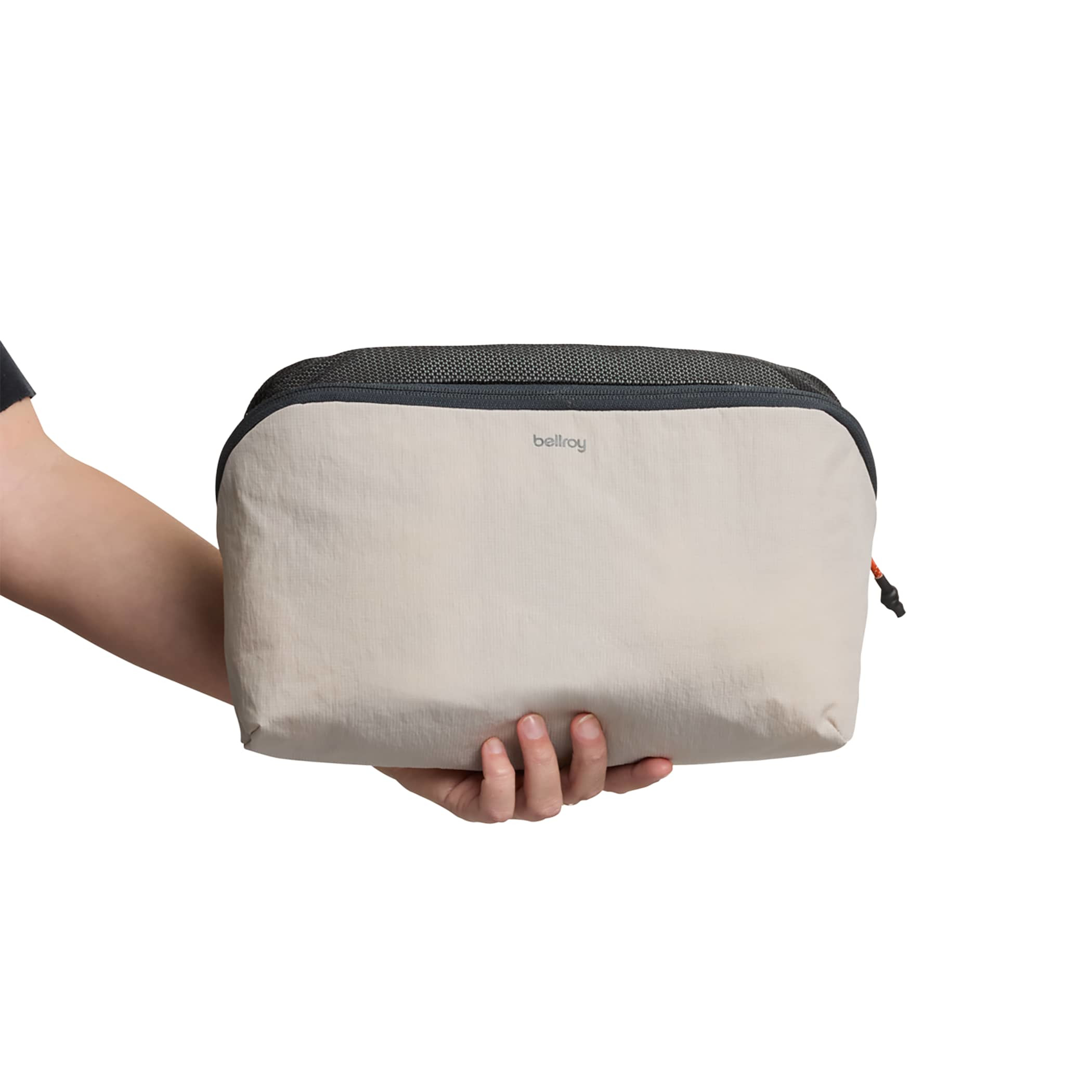 Holding an Ash Bellroy 6L Lite Packing Cube in lightweight Dura Lite nylon with mesh panels, pop-top zip opening, and compact travel organizer design for packing clothes and essentials.