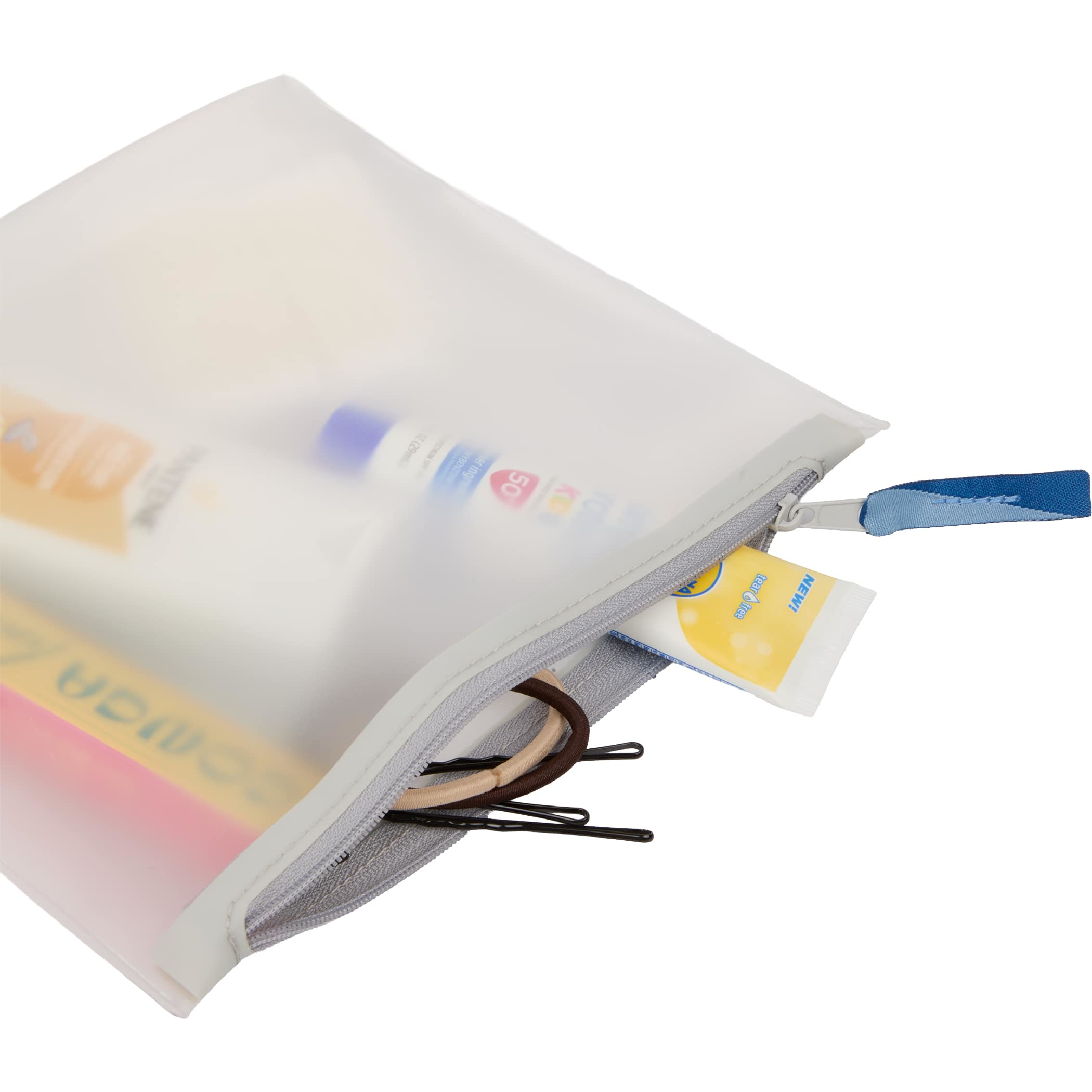 Clear Wander & Roam Travel Pouch in TPU with a gray zipper and blue pull tab, shown holding travel-size toiletries, lip balm, hair ties, and small personal accessories for organized travel storage.