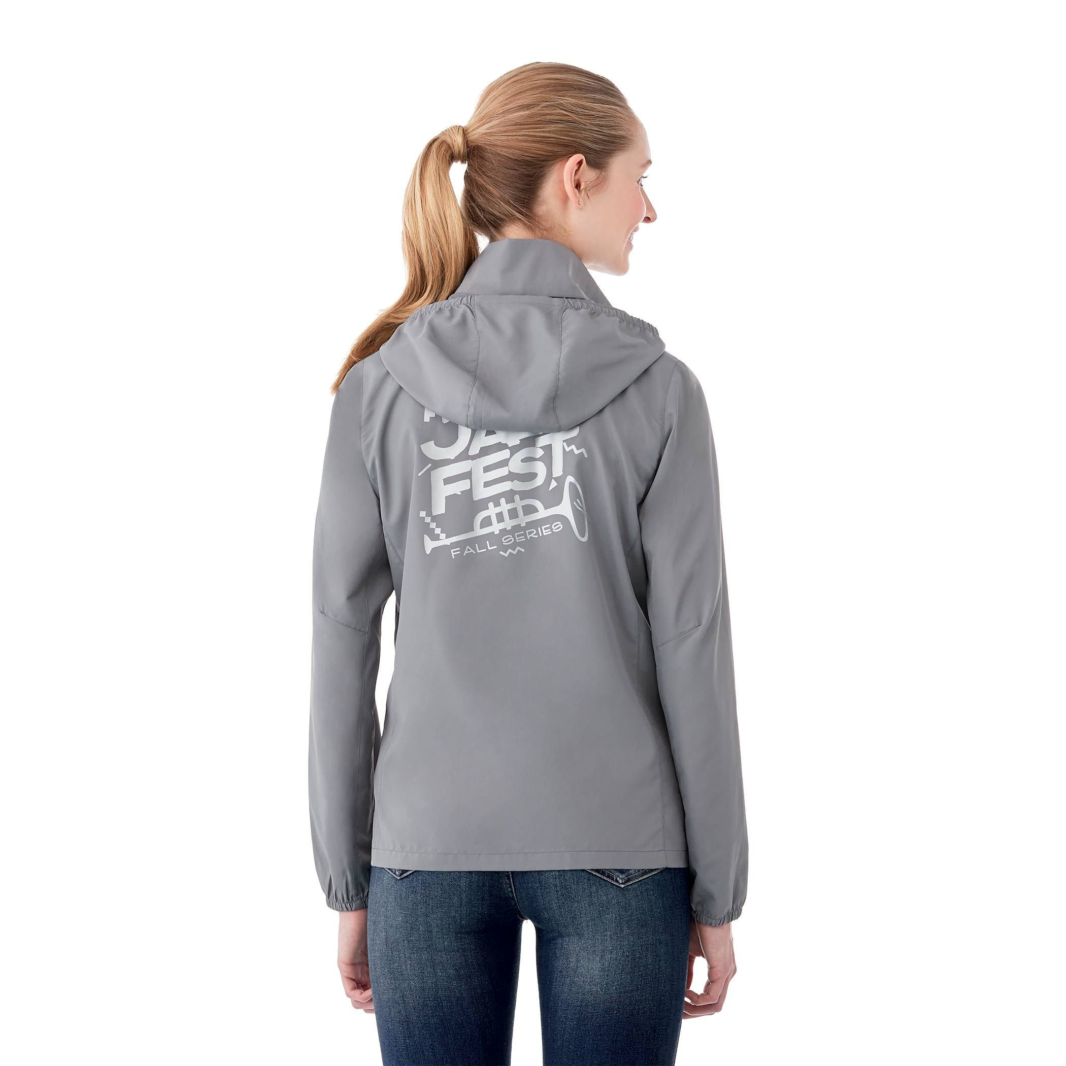 A Woman wearing Quarry Women’s Toba Packable Jacket in a lightweight outerwear design made from water-resistant polyester fabric, featuring a full front zipper, adjustable roll-away hood, articulated sleeves, and a slightly tapered waist for a feminine fit. The jacket has a smooth, matte finish and is designed for packable convenience, folding into its own pocket for easy travel and weather protection.