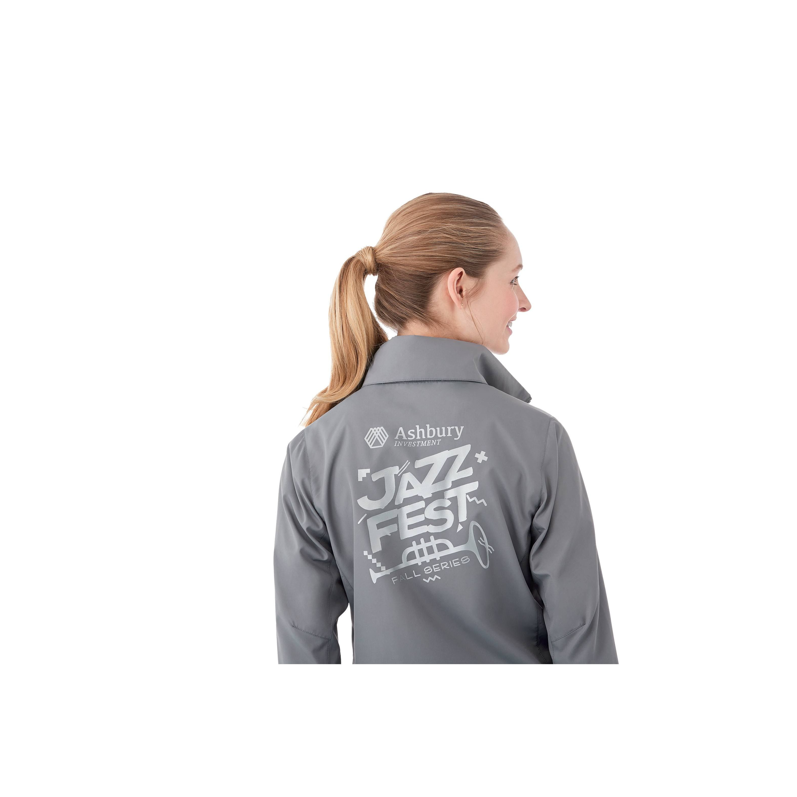 A Woman wearing Quarry Women’s Toba Packable Jacket in a lightweight outerwear design made from water-resistant polyester fabric, featuring a full front zipper, adjustable roll-away hood, articulated sleeves, and a slightly tapered waist for a feminine fit. The jacket has a smooth, matte finish and is designed for packable convenience, folding into its own pocket for easy travel and weather protection.