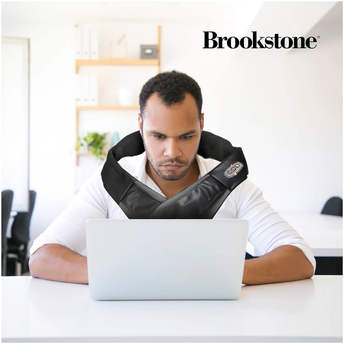 Brookstone Shiatsu Neck and Shoulder Massager in black with ergonomic wraparound design, dual arm straps, and built-in kneading massage nodes for heated neck, shoulder, and upper back muscle relief.