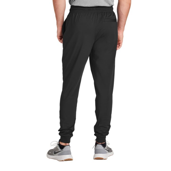 Black Sport-Tek® Sport-Wick® Stretch Jogger, featuring lightweight moisture-wicking stretch fabric, an elastic waistband with adjustable drawcord, tapered legs with elastic cuffs, and zippered side pockets for training, travel, and everyday active wear.