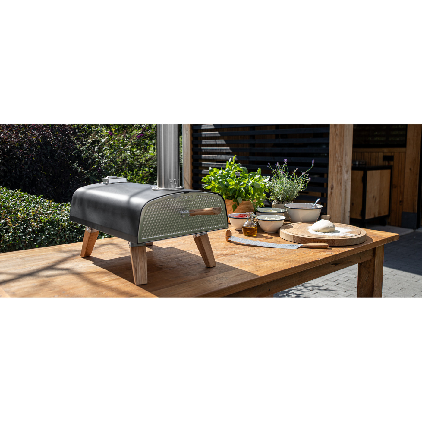 Black outdoor pizza oven with stainless steel construction and stylish European oak accents, designed for high-temperature wood pellet cooking and crispy homemade pizza.