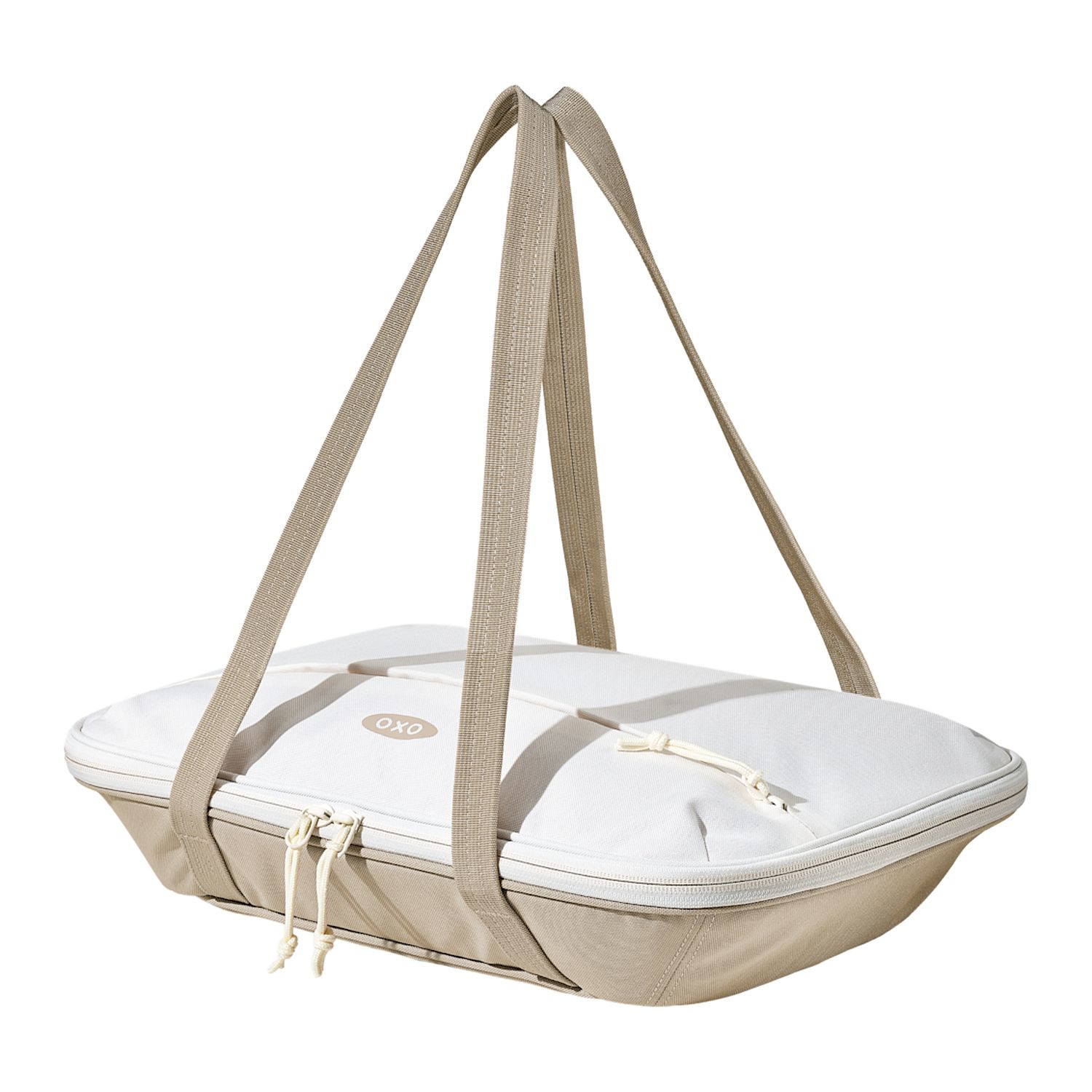 Tan OXO Good Grips Insulated Bakeware Carrier with durable exterior fabric, insulated interior with aluminum lining, generous carry handles, and a front zippered pocket, designed to transport 9 x 13-inch bakeware and keep hot or cold dishes at temperature during potlucks, parties, and family gatherings.