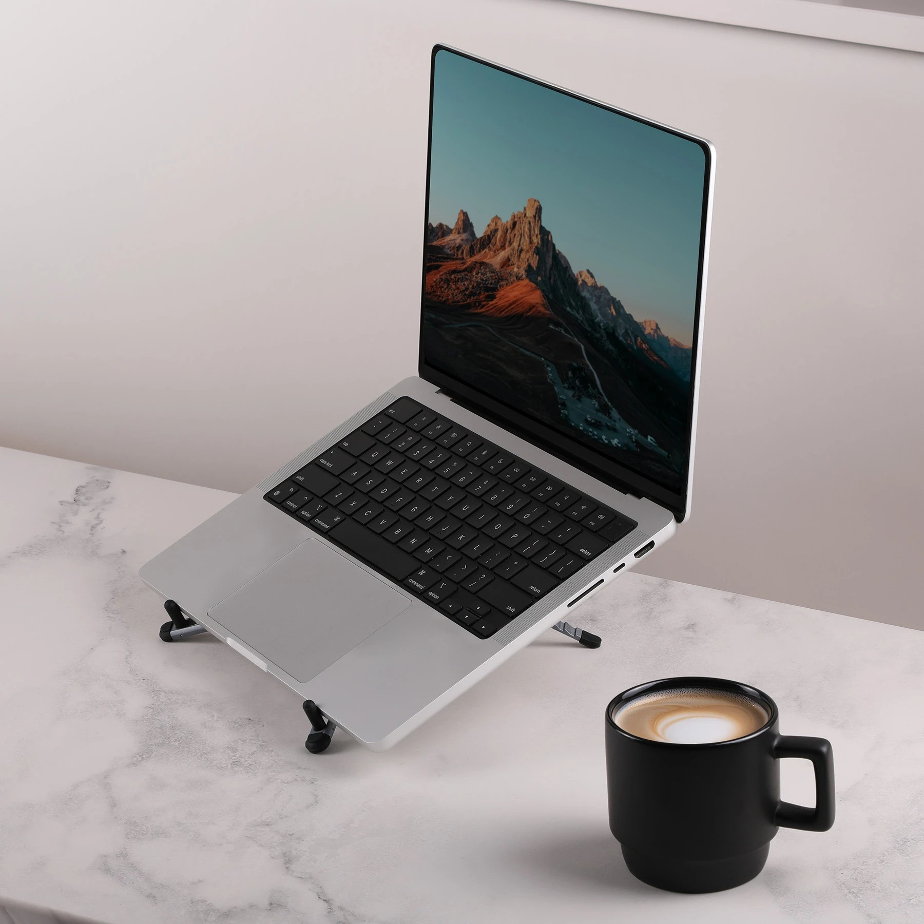 Gray Magnix Portable Travel Laptop Stand Compact, adjustable laptop stand with sleek metal legs and a magnetic phone mount, shown in a modern metallic finish. Folds flat for easy travel and supports laptops, tablets, and phones for portable workspaces.
