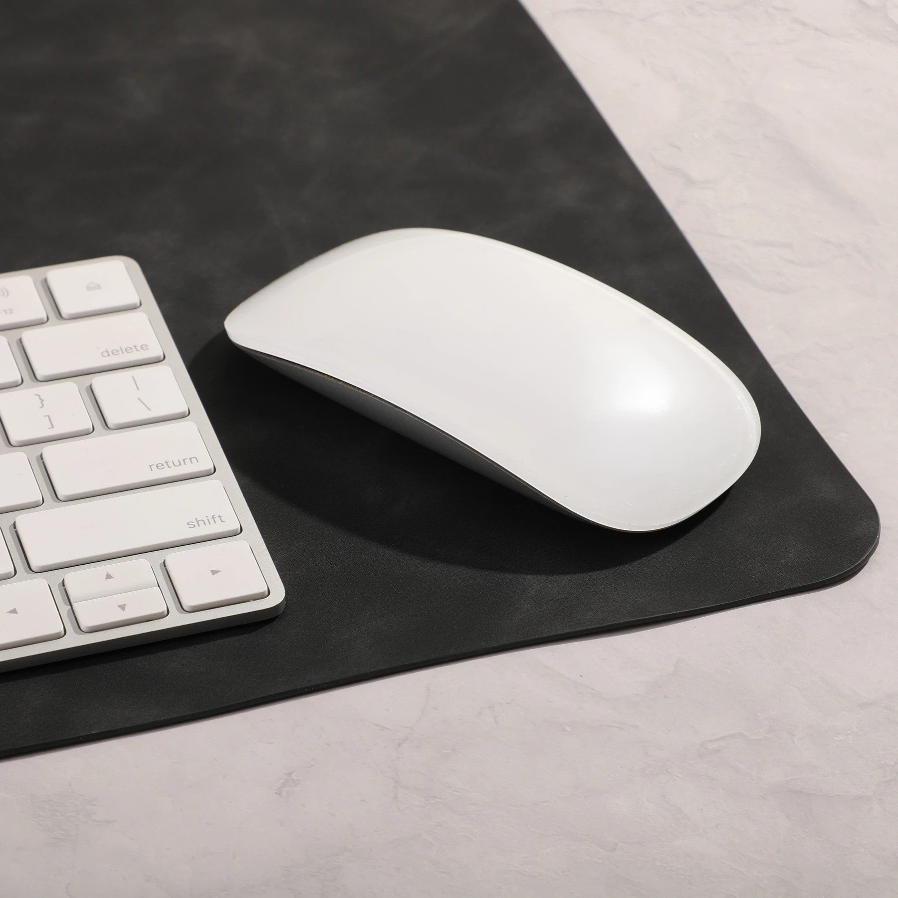 Black Desk Mat Pro Desk Mat in a sleek black PU material with a smooth soft-touch surface, shown as a wide rectangular desk mat designed to cover and protect a desktop workspace.
