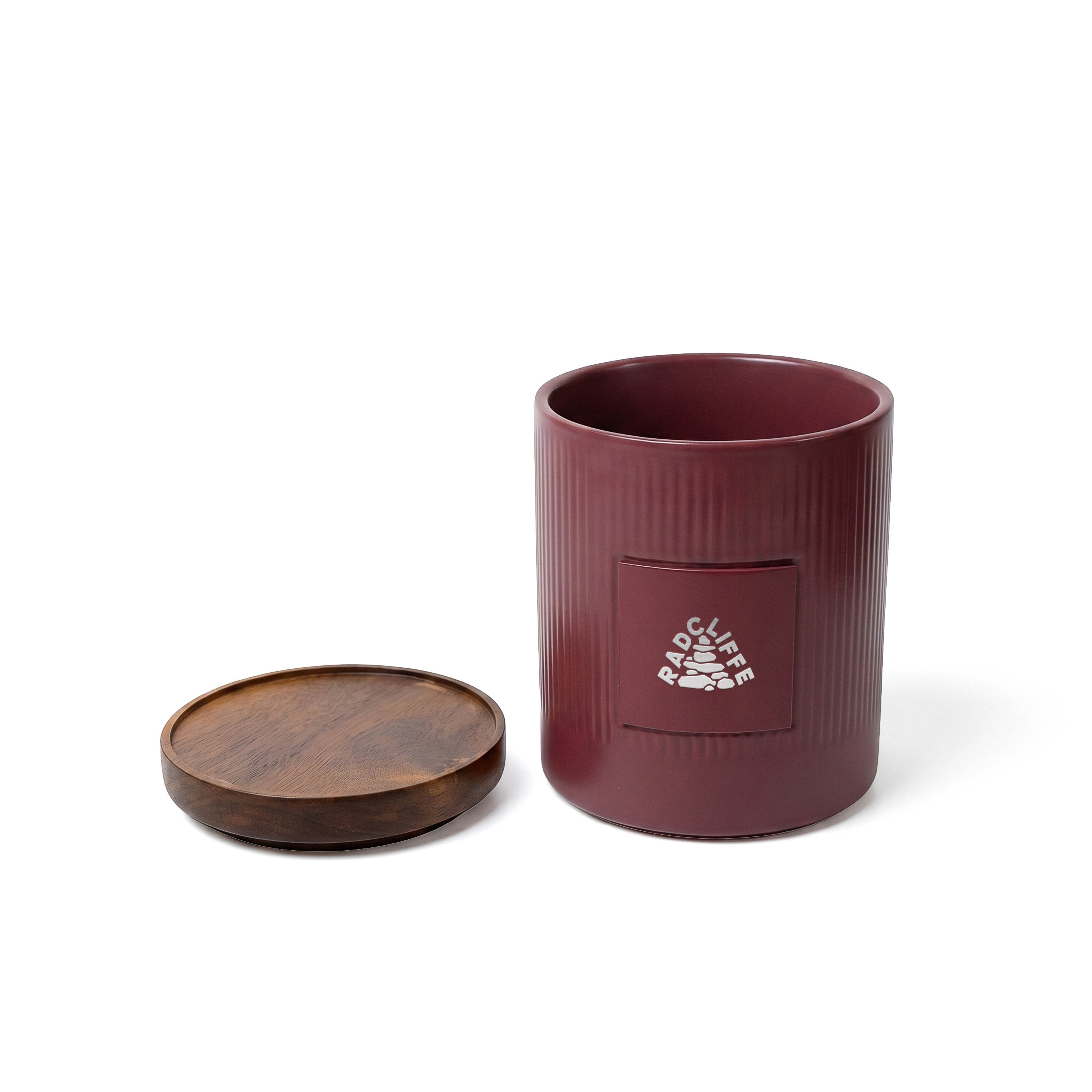 Burgundy stoneware utensil holder and spatula set with silicone spatulas, acacia wood handles, acacia wood base, and metal plate for branding.