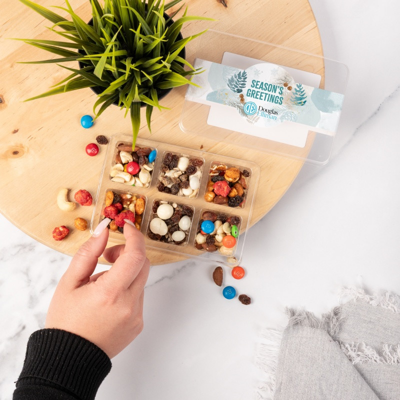 Clear mini tackle box with six compartments containing Rainbow Delight, yogurt raisin trail mix, and energy trail mix, featuring a customizable full-color sleeve.